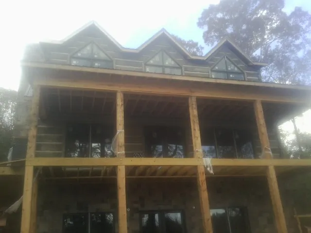 Dormers and porch framing on a large log home under construction — Roof Coating work by our crew in Berry